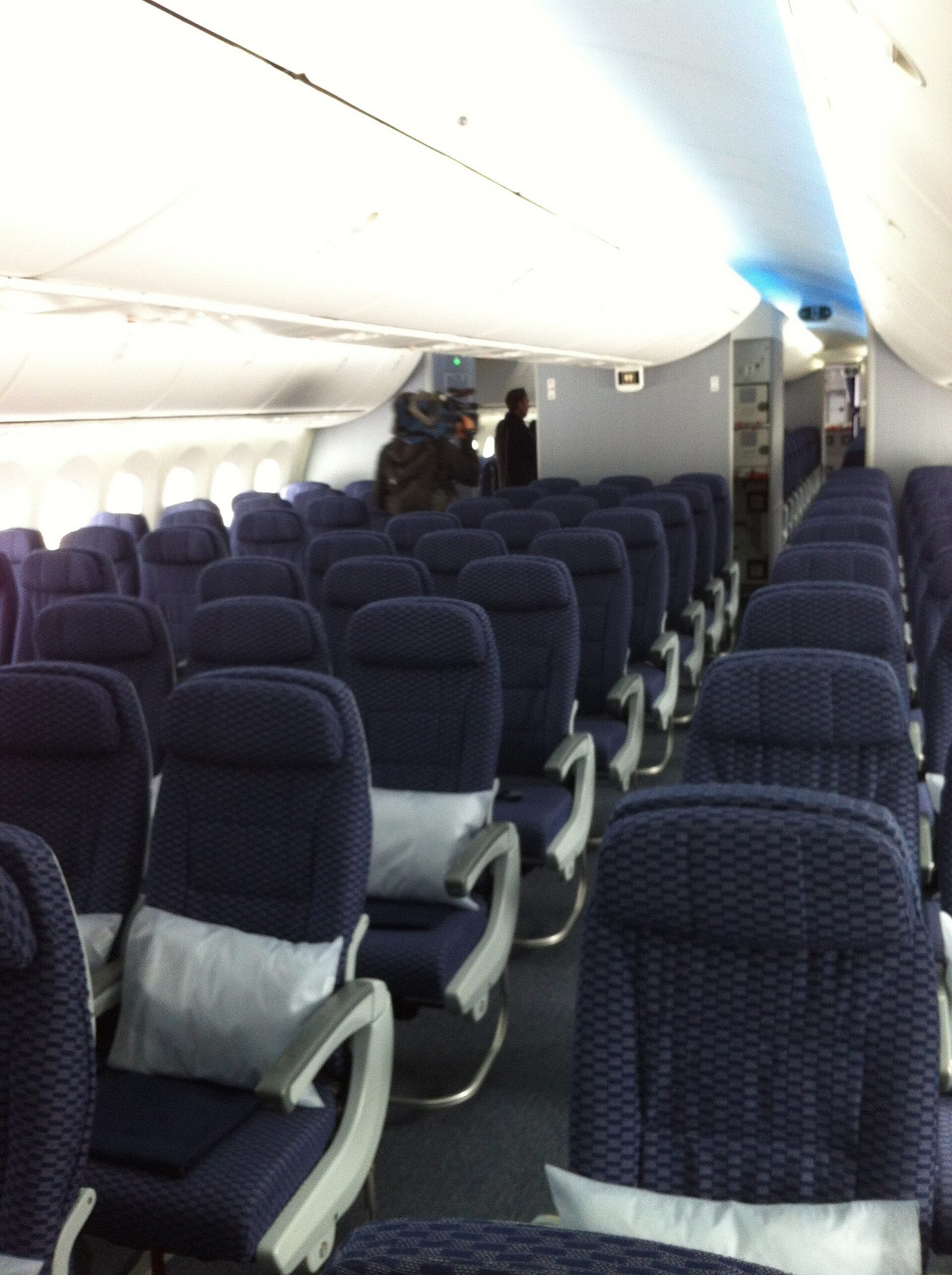 Rows of empty dark-blue economy seats inside a wide-body jet cabin