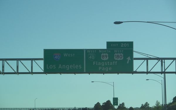 A green overhead interstate sign for I-40 West to Los Angeles and Exit 201 to Flagstaff and Page, above an open highway under a clear sky