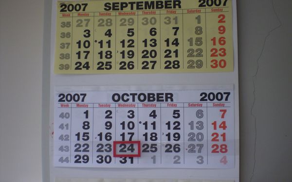 A paper wall calendar showing September and October with one date outlined in a red frame