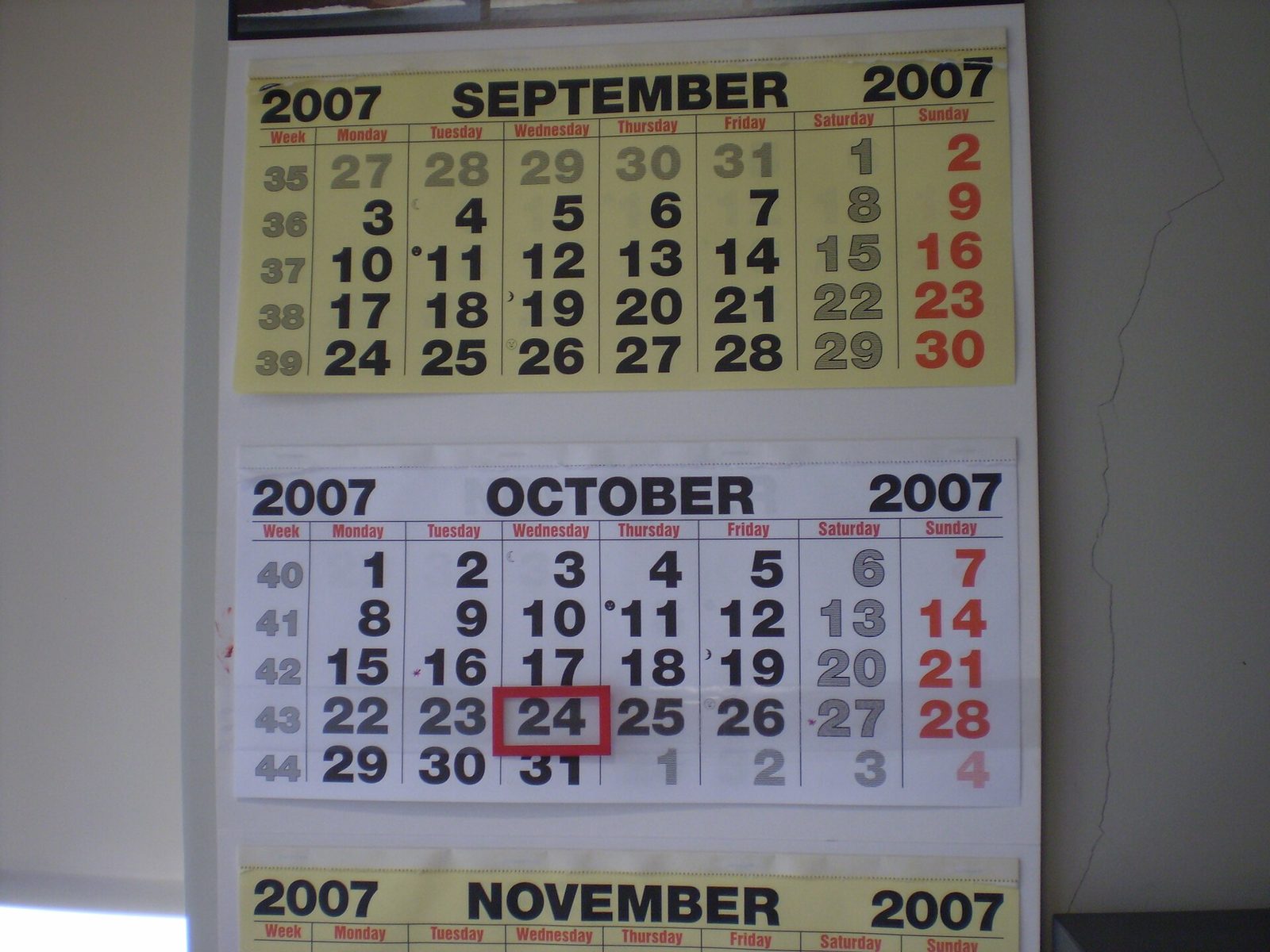 A paper wall calendar showing September and October with one date outlined in a red frame
