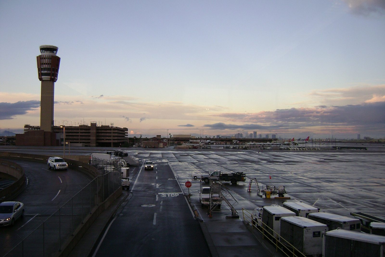 Phoenix Sky Harbor Airport at dusk, with the control tower, a parking garage, wet airport roads and the Phoenix skyline in the distance