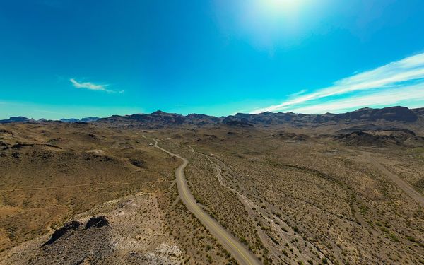 Aerial view of a two-lane stretch of Historic Route 66 winding through brown desert toward the Black Mountains near Oatman, Arizona