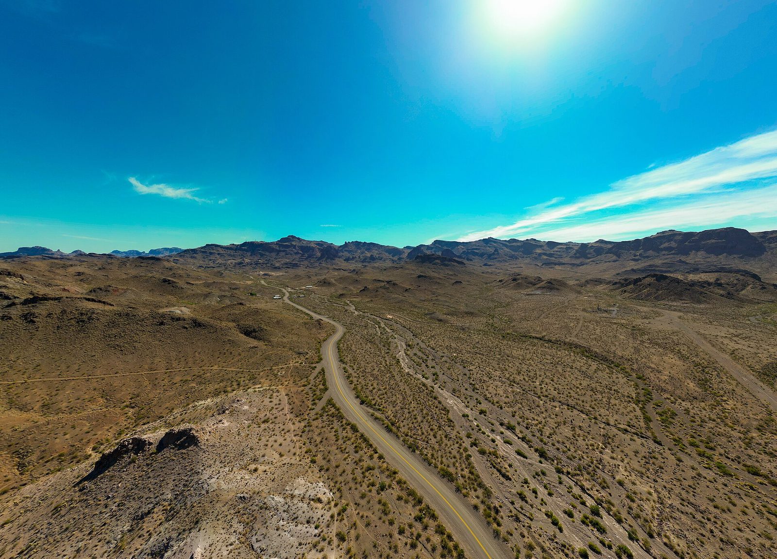 Aerial view of a two-lane stretch of Historic Route 66 winding through brown desert toward the Black Mountains near Oatman, Arizona