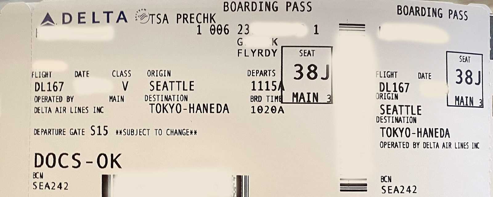 Close-up of a printed airline boarding pass with the words "TSA PRECHK" printed near the top, with personal details blurred out
