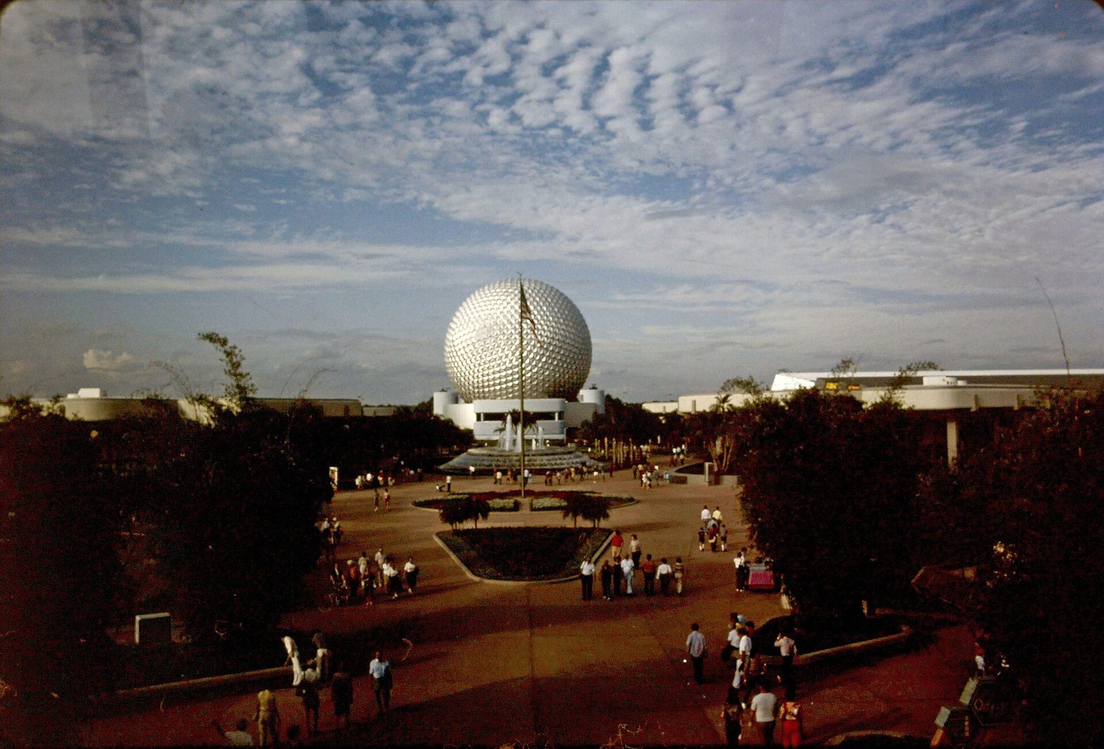 EPCOT Center in 1983, with the silver geodesic sphere of Spaceship Earth behind a fountain plaza and guests walking along the paths